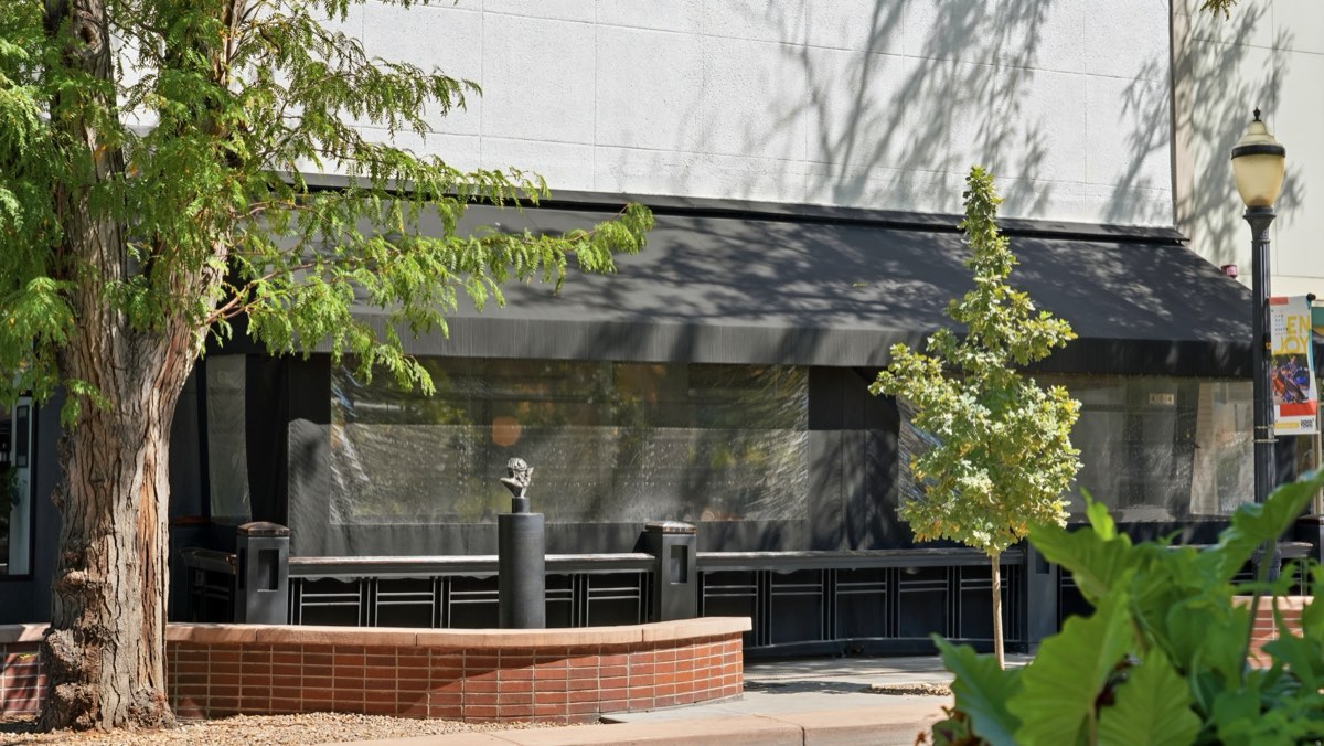 A black awning and screened enclosure over the Bin 707 restaurant patio, seen from the street