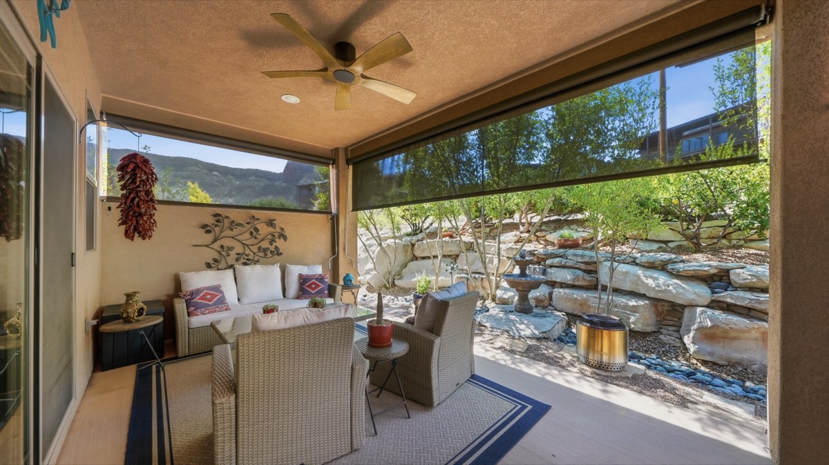 A covered home patio with wicker seating and roll-down shade screens across the open sides